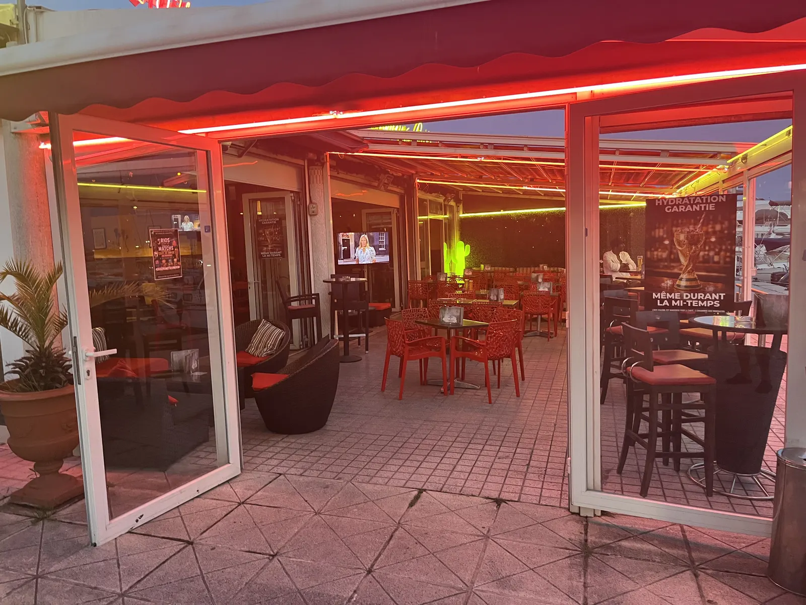 Ambiance nocturne à Rio's Banana Café, terrasse illuminée en néon rouge sur le port